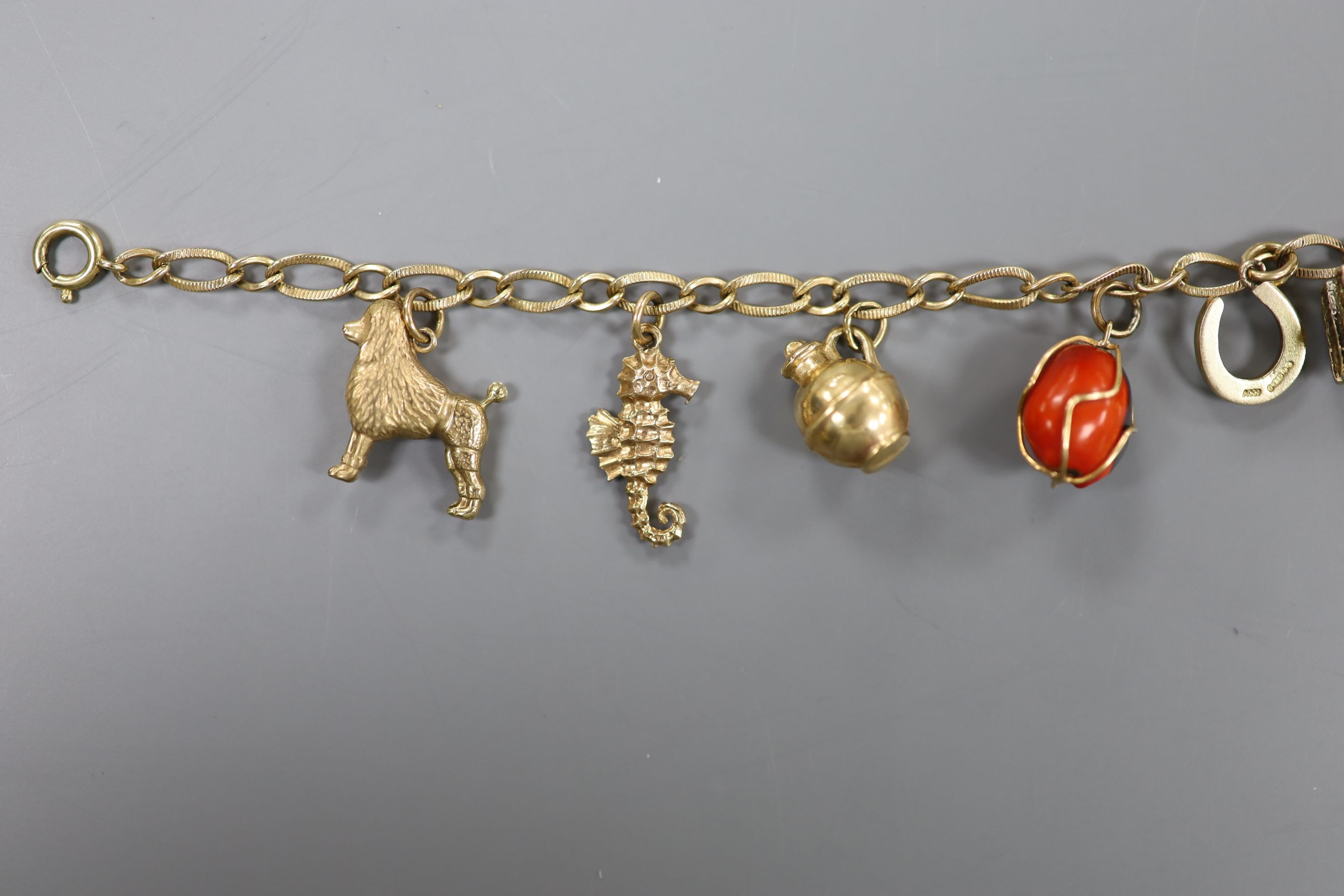 A 10k yellow metal oval link charm bracelet, hung with assorted mainly 9ct gold charms, gross weight 17.7 grams.